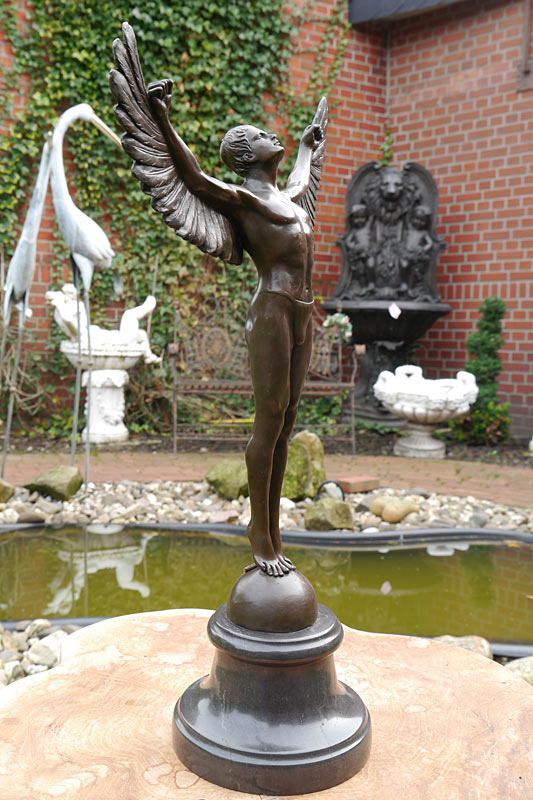 Die Skulptur steht mit ausgebreiteten Flügeln auf einem Sockel
